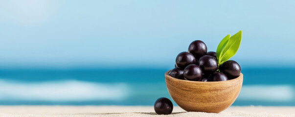 A bowl of acai sits on a sandy surface with a serene ocean backdrop, showcasing freshness and natural beauty.