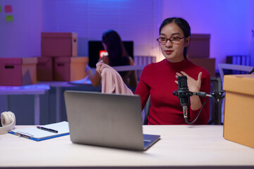 Content creator records a fashion podcast in a home studio, surrounded by boxes and using a laptop...