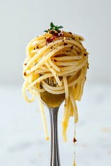 Realistic close-up of twirled spaghetti on a silver fork, coated in olive oil & spicy seasoning with dripping sauce & chili garnish. Appetizing food photo on white background