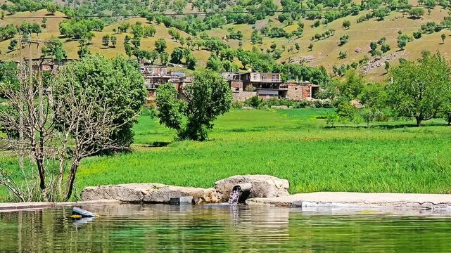 A tranquil pond reflects lush greenery and distant mountains under a clear blue sky.
📍Marivan - Kurdistan 