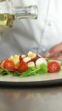 Chef putting oil on a salad