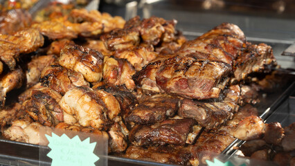Juicy roasted pork ribs on a tray for sale at the food market. Delicious food