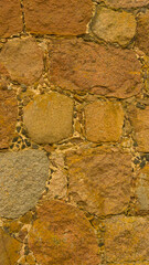 An old stone wall. Masonry. Background of yellow stones. The texture of the stone. Vertical image.