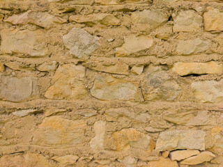 The old yellow stone wall. Yellow stone background. The texture of the stone.