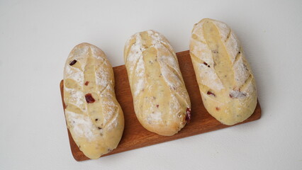 Three pieces of cranberry cream cheese bread on a wooden plate isolated on a white background.