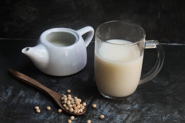 Drink a glass of soybean milk with soybeans on a black background