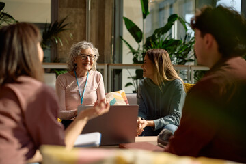 Happy university teacher enjoying in communication with her students.