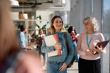 Happy student and her college teacher walking through hallway.