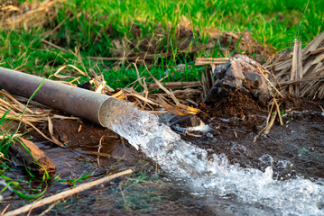 Obraz premium pump pipe water flow equipment agriculture, pump pipe water flow equipment agriculture, Water from a well filled a pond for irrigation,Irrigation water from the source