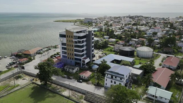 Drone facing east flies south over New Town Barracks neighborhood on sunny morning in Belize City