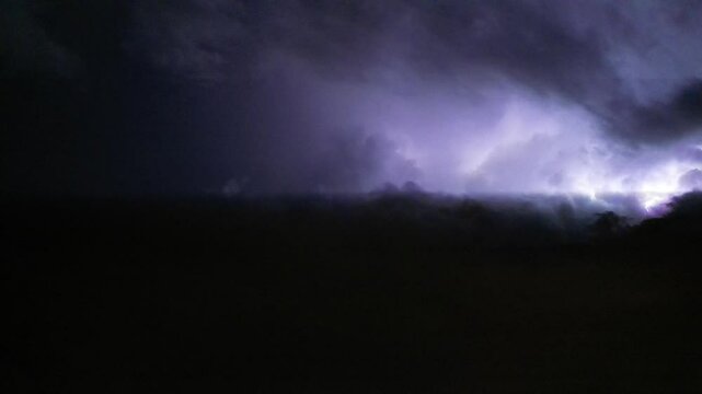 Breathtaking low angle footage of the lightning flashing in the dark night sky during a thunderstorm