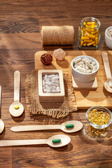 Dietary supplements, vitamins and minerals such as vitamin d3, a, b, c, e, k, magnesium, zinc and multivitamin pills in small plates on wooden desk on a wooden background in sunshine. Rustic style.