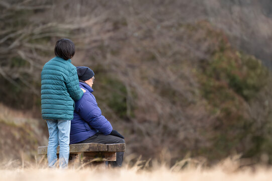 ベンチに座る高齢男性に寄り添う若者