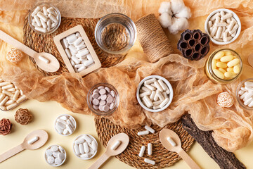 Glass of water, many food supplements in forms of tablets, pills and capsules from above on beige background in rustic style. Dietary supplements, vitamins and minerals for healthy lifestyle.