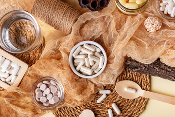 Glass of water, many food supplements in forms of tablets, pills and capsules from above on beige background in rustic style. Dietary supplements, vitamins and minerals for healthy lifestyle.