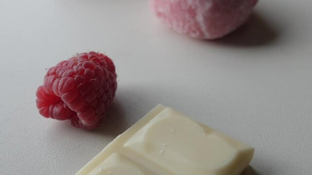 Fresh raspberries and white chocolate on a light surface for a sweet dessert concept