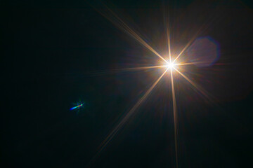 Bright sunlight shine creates lens flare light leak effects in dark background.