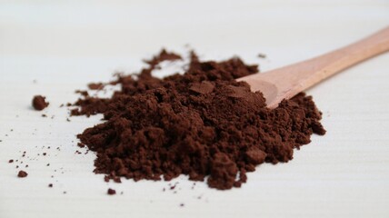 Coffee powder on wooden spoon isolated on wooden background