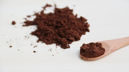Coffee powder on wooden spoon isolated on wooden background