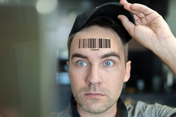 young man with a qr code on his forehead. A man with a stupid expression looks at his qr code on his head. The concept of chipping the population. global control and governance