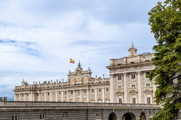 Naklejka premium Madrid, Spain - october 02, 2024: Facade of the Royal Palace of Madrid with tourists walking around in Madrid, Spain