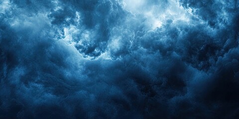 Fototapeta premium Dramatic dark storm clouds fill the sky in shades of deep blue and gray, creating a textured, moody atmosphere with ample negative space for text.