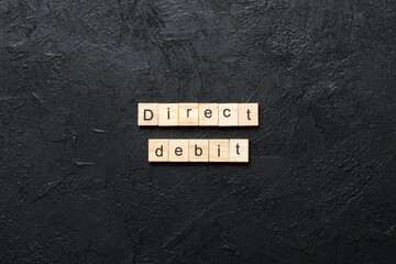 direct debit word written on wood block. direct debit text on cement table for your desing, concept