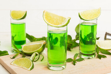 Sweet refreshing mint liqueur, with ice and mint leaves on table background, Shots with lime slice and mint flat lay