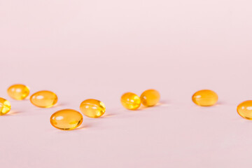 Heap of yellov pills on colored background. Tablets scattered on a table. Pile of red soft gelatin capsule. Vitamins and dietary supplements concept