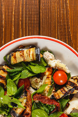 Colorful grilled vegetable salad with leafy greens and tomatoes