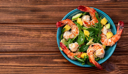 Salad with tiger shrimps , avocado and mango . Top view