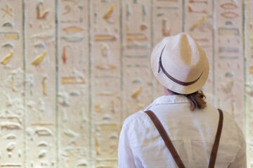 Woman with hat looking at the hieroglyphs of the Egyptian Temple