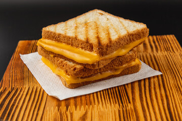 Delicious grilled cheese sandwich stacked on a wooden board