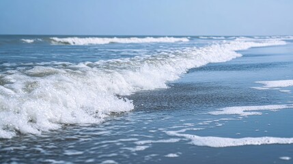 Fototapeta premium Pale blue sea surface with waves and foam at high tide