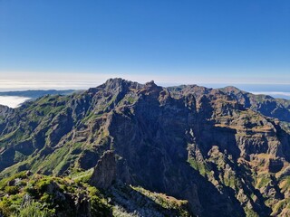 Fototapeta premium Incredible mountain landscape view, hike from Pico do Arieiro to Pico Ruivo, Madeira, steep cliffs and deep valleys, vibrant blue sky