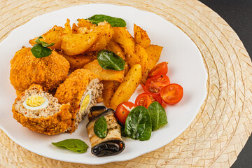 Crispy chicken nuggets with roasted potatoes and fresh vegetables on a plate
