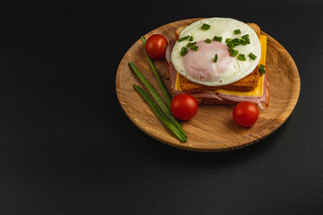 Tasty breakfast sandwich with poached egg and veggies on wood plate