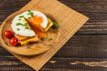 Delicious breakfast sandwich with fried egg and fresh tomatoes on wooden table