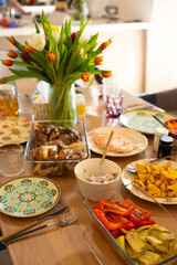 Festive dining table with home-cooked meals and tulip bouquet