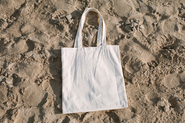 White cotton or mesh bag on beach sand background. Zero waste, no plastic, eco friendly shopping,...