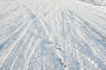car tire marks on snowy road.