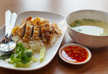 Deep-fried checked over rice or Kaw Mon Kaitodd in Thai language. Popular easy Thai-Chinese food menu with deep-fried chicken rice and sweet dipping sauce, cleared soup. Real image with natural light.