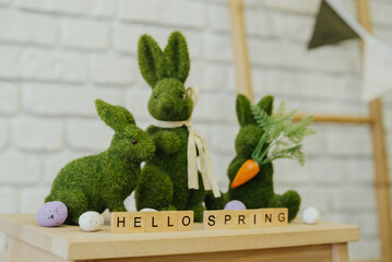 Spring decoration featuring moss bunnies and festive text on a wooden surface