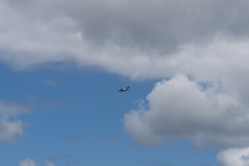 Fototapeta premium A military transport aircraft soars through a picturesque sky, leaving a trail against a backdrop of fluffy white clouds.