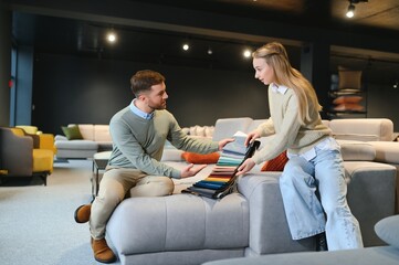 Couple choosing sofa and pillows at furniture store