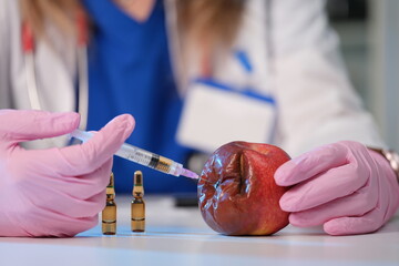 A scientist is seen injecting an apple, demonstrating advanced methods in food safety research and...
