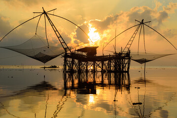 Golden Hour Serenity: Traditional Thai fishing nets silhouetted against a vibrant sunset sky. Perfect for your next travel or nature-themed project.