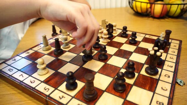 Closeup of a boy hand moving the queen piece on a chess board