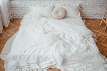 Cozy bedroom with rumpled white bedding and natural light