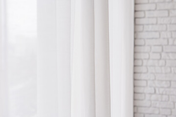 Obraz premium Soft white curtains draping elegantly near a brick wall during daytime